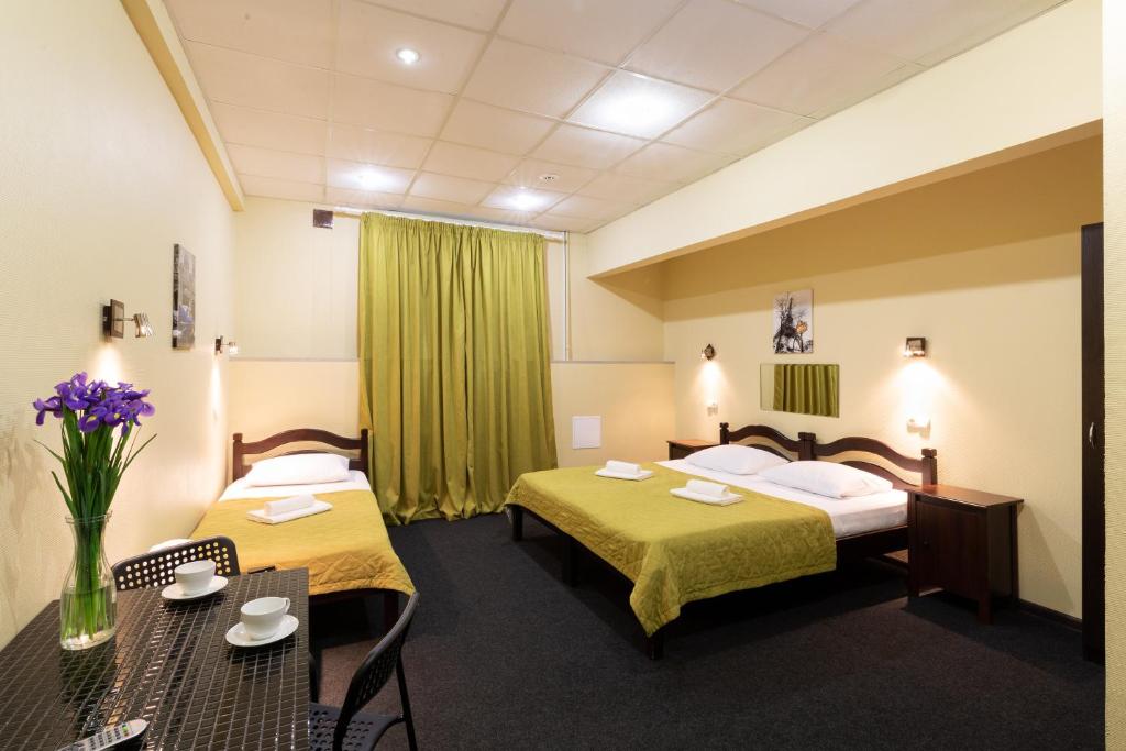 モスクワにあるSemenovskiy Mini Hotelのベッド2台とテーブルが備わるホテルルームです。