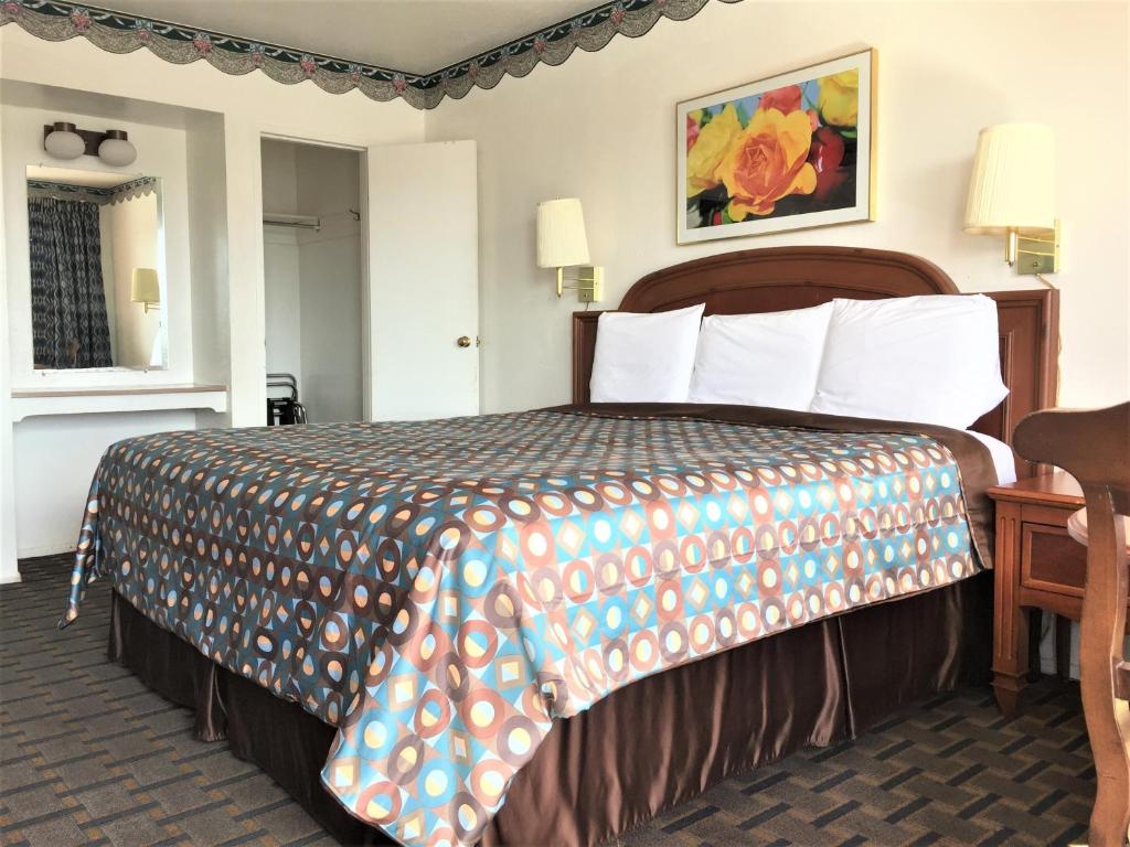 a hotel room with a bed with a colorful bedspread at Ramblin Rose Motel in Kingman