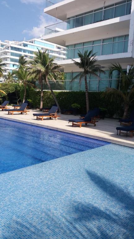 a swimming pool with palm trees and a building at Cartagena Beach Condo - 1400 sq. Ft. (130 m2) in Cartagena de Indias