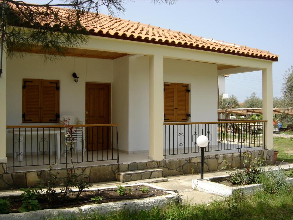 a small white house with a balcony and wooden doors at House Rena in Vourvourou