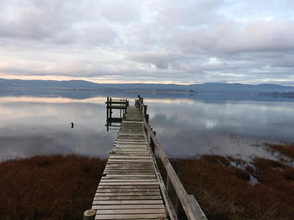 a dock on a lake with a person standing on it at Tamar House in Rosevears