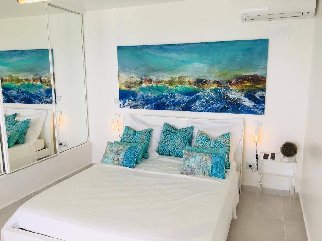 a bedroom with a white bed with blue pillows at Studio Cozy Mélissa Élégance - GUADELOUPE , LE GOSIER , DAMPIERRE - AVEC PLEINE VUE MER - OCÉAN à 180 degrés in Le Gosier