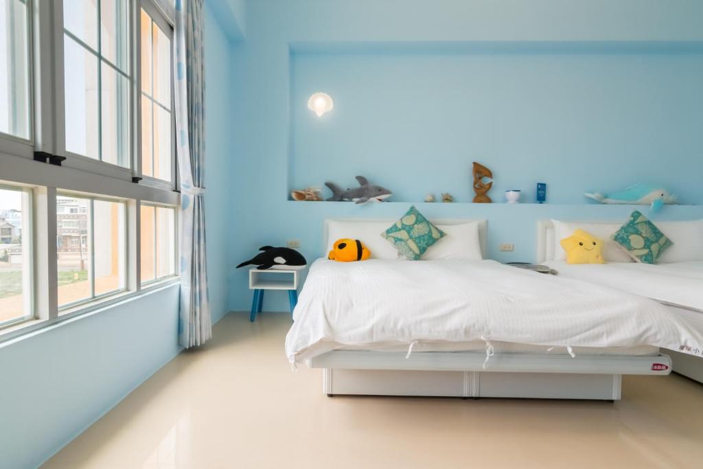 a bedroom with two beds and a blue wall at Ciao Life B&amp;B in Taitung City
