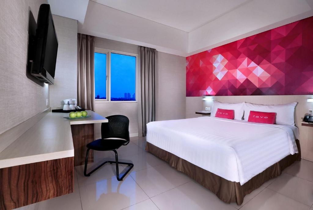 a bedroom with a large bed with a pink wall at favehotel Tanah Abang - Cideng in Jakarta