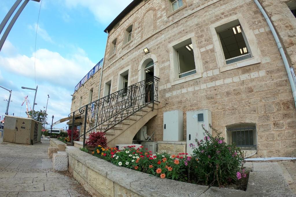 Haifa Hostel في حيفا: مبنى من الطوب عليه درج وزهور