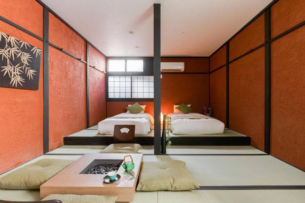 Una habitación con dos camas y una mesa dentro. en NAKAZ Machiya , Osaka Umeda, en Osaka