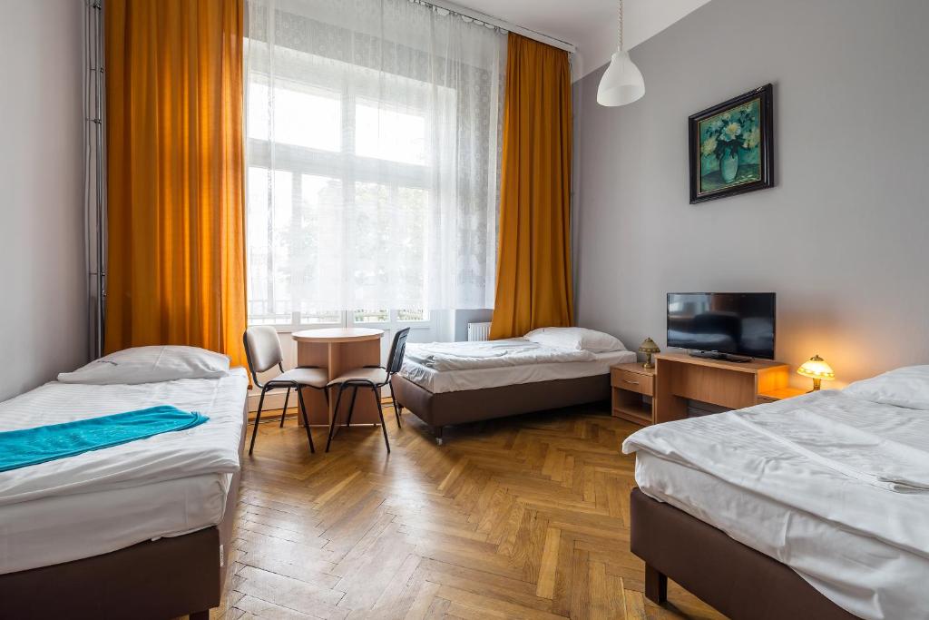 um quarto com duas camas, uma mesa e uma TV em Savoy Wrocław em Breslávia