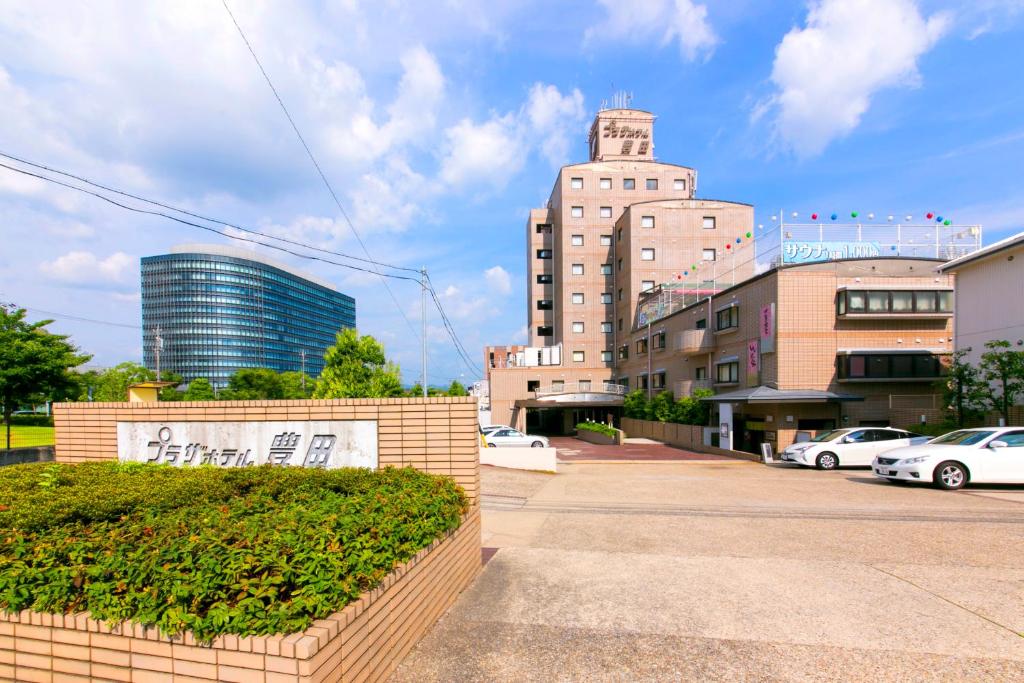 een stadsstraat met auto's geparkeerd voor gebouwen bij Plaza Hotel Toyota in Toyota