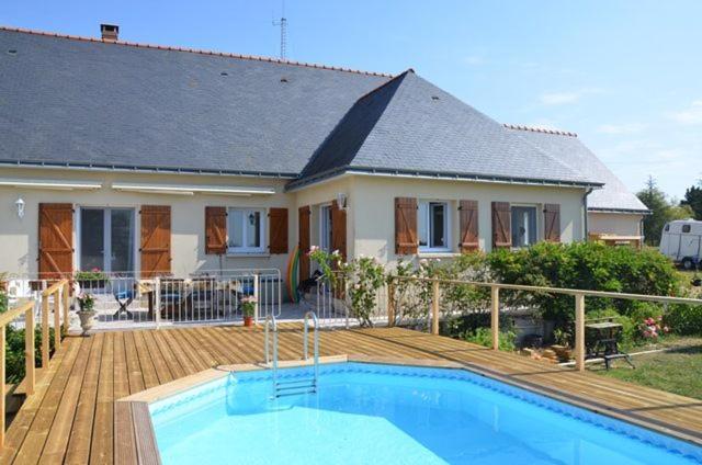 una casa con piscina frente a una casa en Les petits chenes en La Pellerine