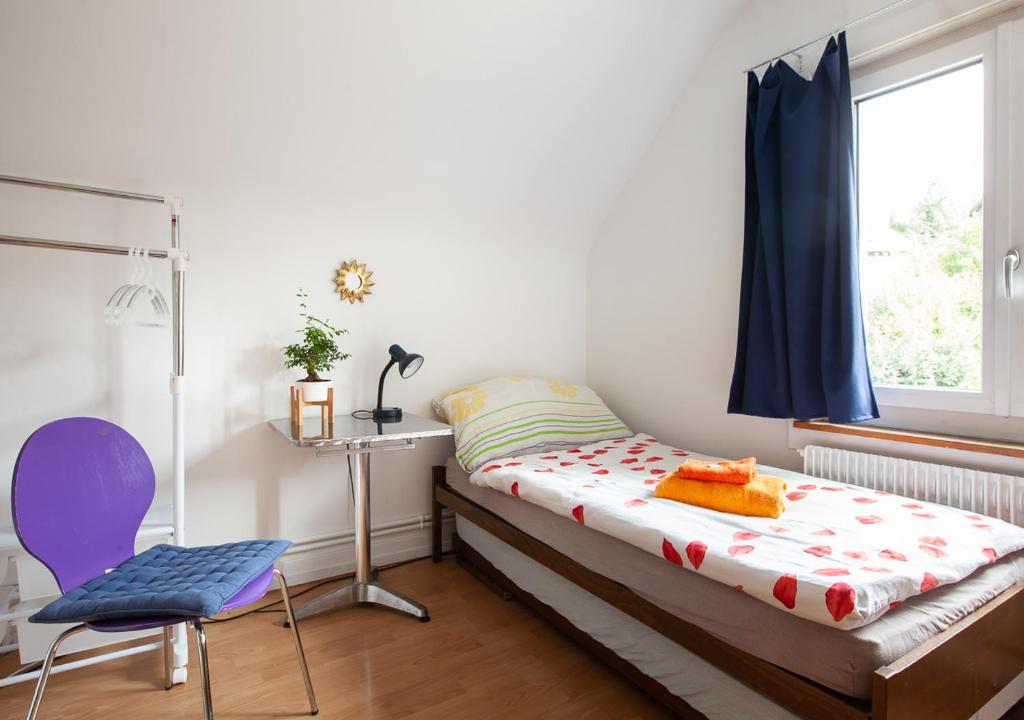 ein Schlafzimmer mit einem Bett, einem Stuhl und einem Fenster in der Unterkunft Bed&Breakfast Pinocchio in Seuzach