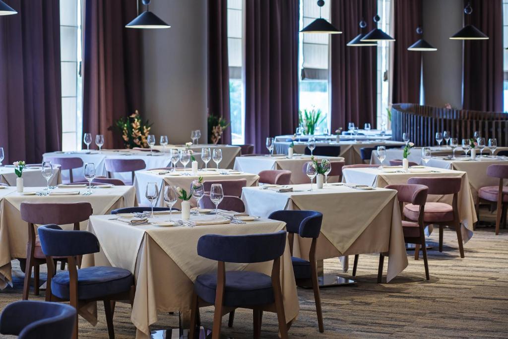 a dining room with tables and chairs with white tablecloths at Марциаль in Tyumen