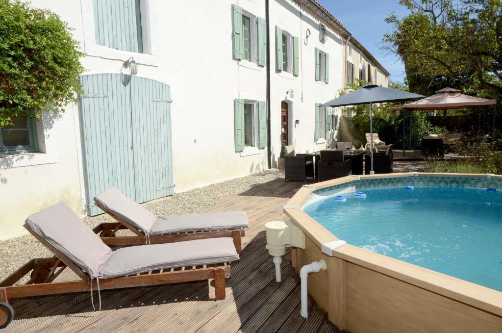 uma piscina com duas espreguiçadeiras ao lado de uma casa em Tournesol em Carlipa