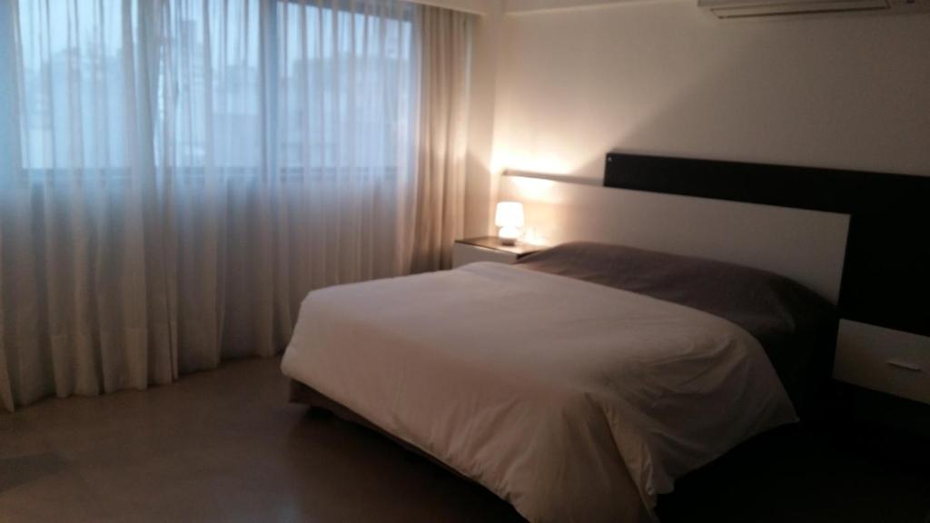 1 dormitorio con cama blanca y ventana en Rosario Paladium Apartment en Rosario