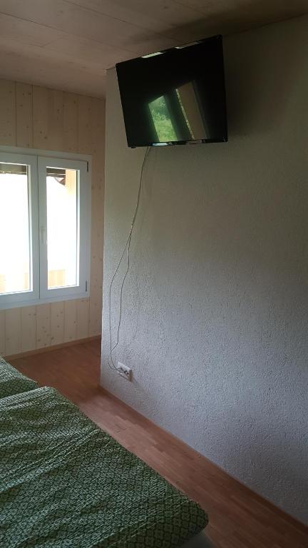 1 dormitorio con TV colgada en la pared en b&b krättli, en Eggiwil