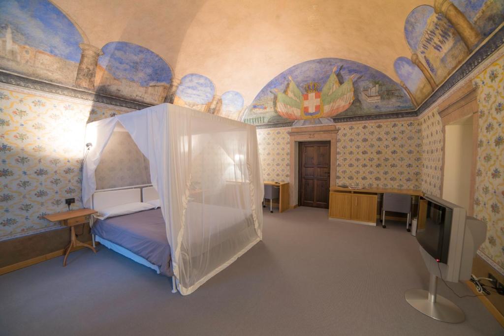 sypialnia z łóżkiem i telewizorem w obiekcie Hotel Cavour Et Des Officiers w mieście Bard