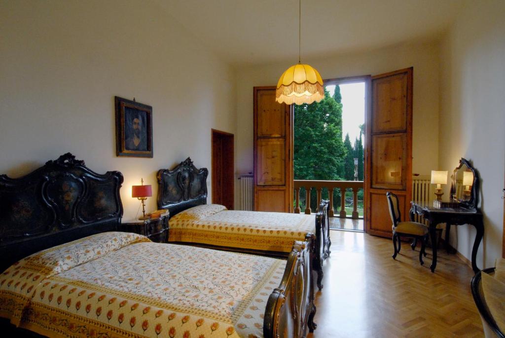 sypialnia z 2 łóżkami, stołem i oknem w obiekcie "Alle Montanine" Villa Poggio w mieście Impruneta