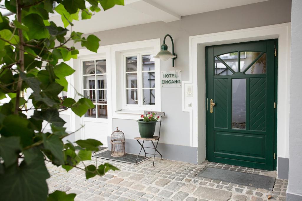 a green door on a house with a plant at Hotel Brummeier in Eferding