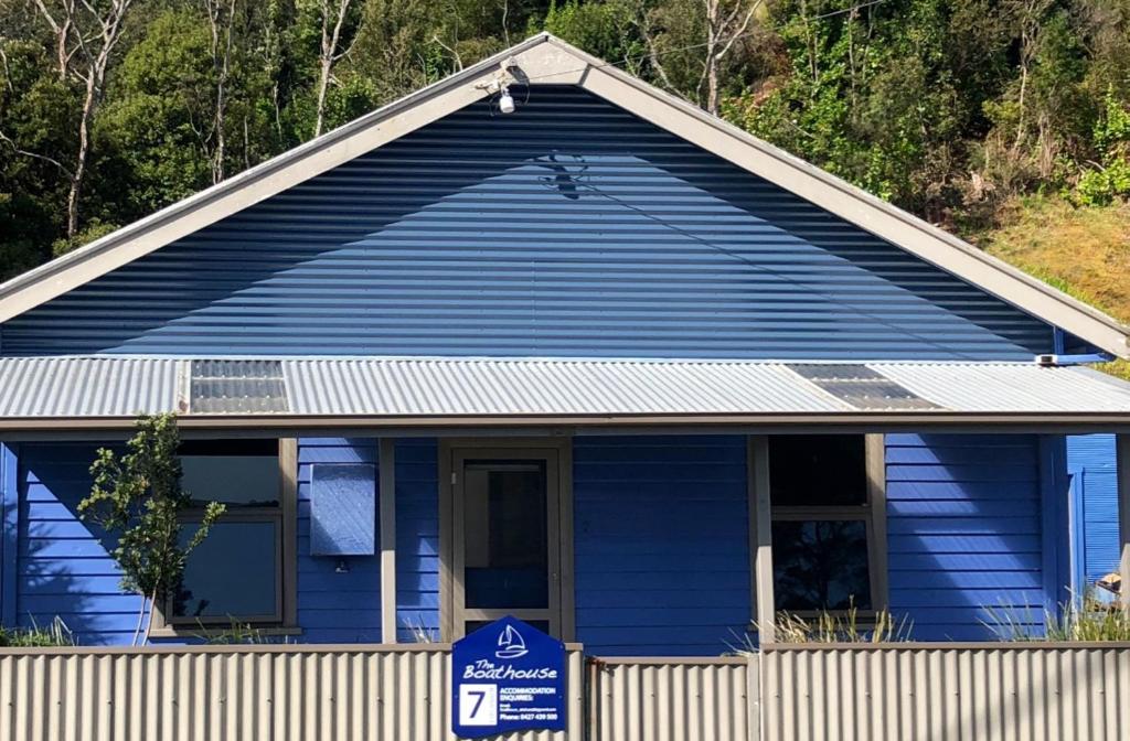 a blue house with a handicapped sign in front of it at The Boat House in Strahan