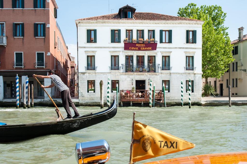 Um homem está numa gôndola num canal. em Canal Grande em Veneza