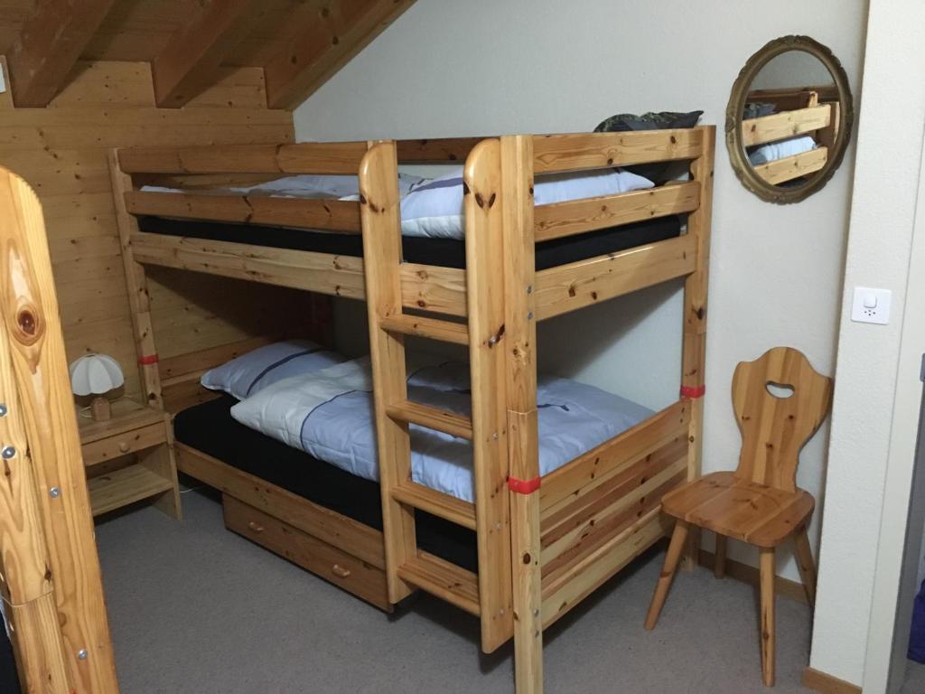 a bunk bed room with two bunk beds and a chair at Chalet Orchis in Hasliberg Wasserwendi