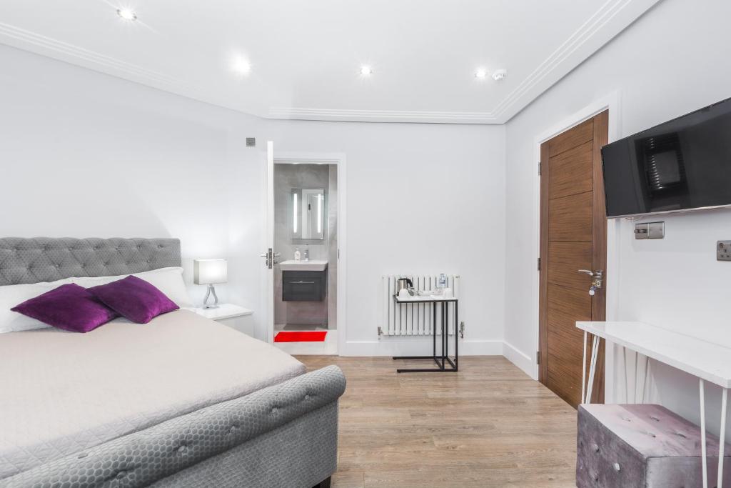 um quarto com uma cama com almofadas roxas em TA House em Edgware