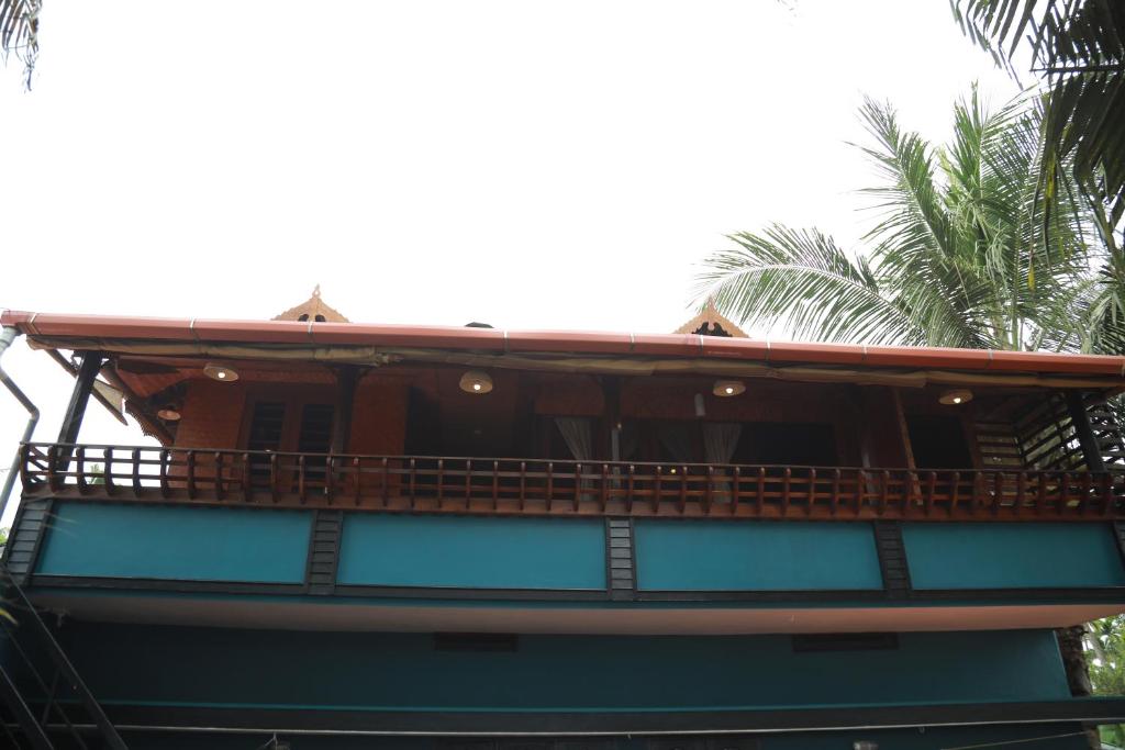 a building with a balcony with palm trees in the background at Sajeev Home Stay in Cherai Beach