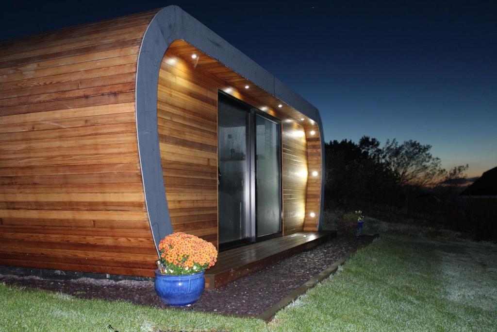 The Pod & Cwtch luxury accommodation في أبيريرون: منزل صغير مع نافذة وزرع الفخار