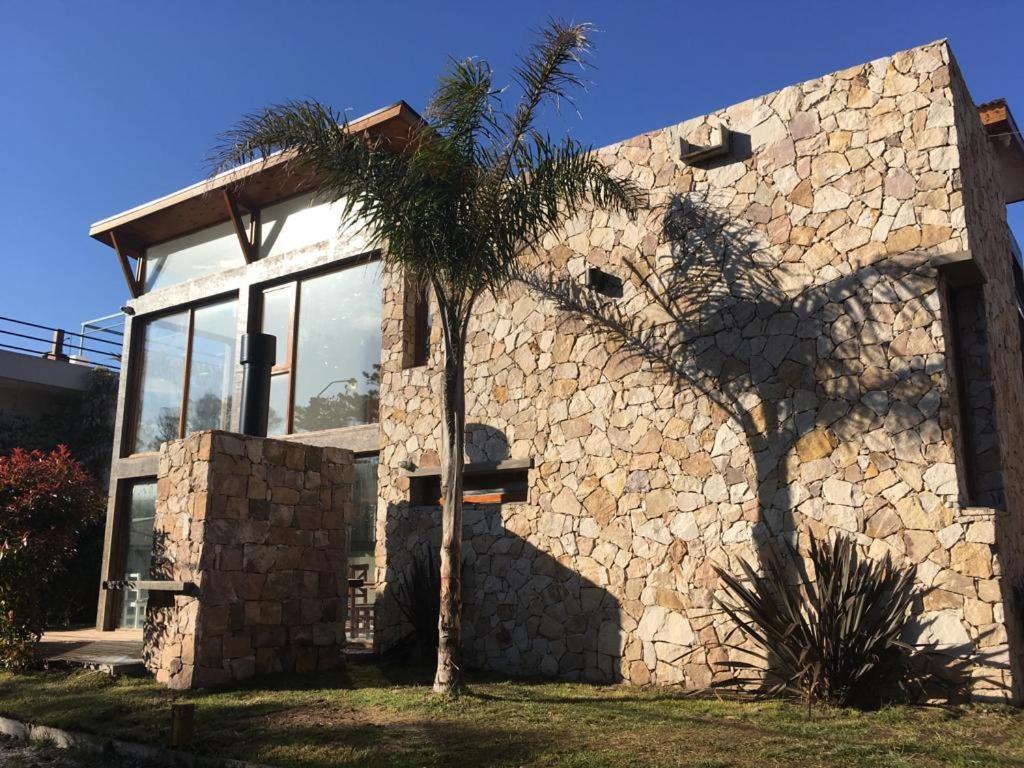 una casa de piedra con una palmera delante de ella en Tila Playa en Las Gaviotas