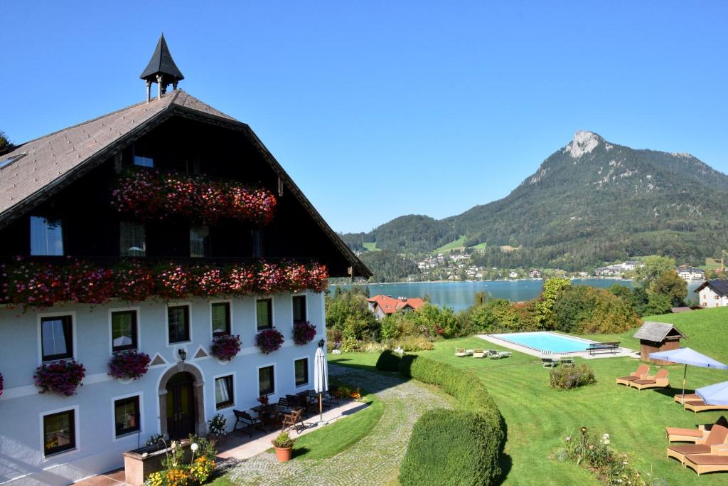 ein Gebäude mit einem Garten und einem Wasserkörper in der Unterkunft Pension Hohenau in Fuschl am See