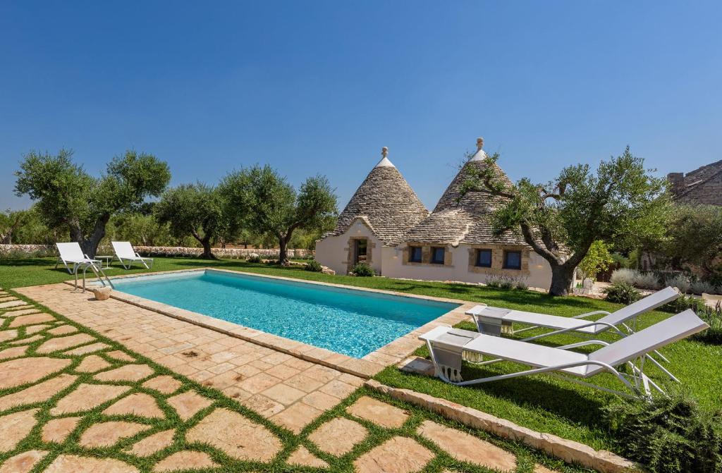 a villa with a swimming pool in front of a house at Trullo Atena in Alberobello