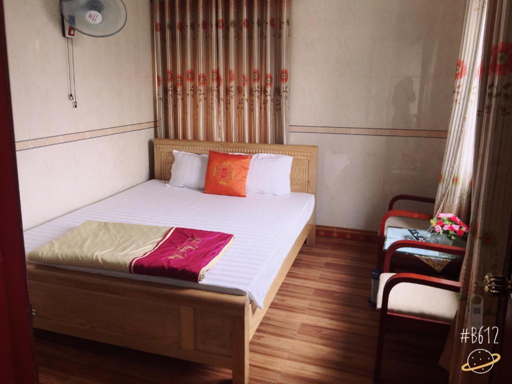 Schlafzimmer mit einem Bett mit weißer Bettwäsche und orangefarbenen Kissen in der Unterkunft Thanh Binh Hotel in Provinz Hà Tĩnh