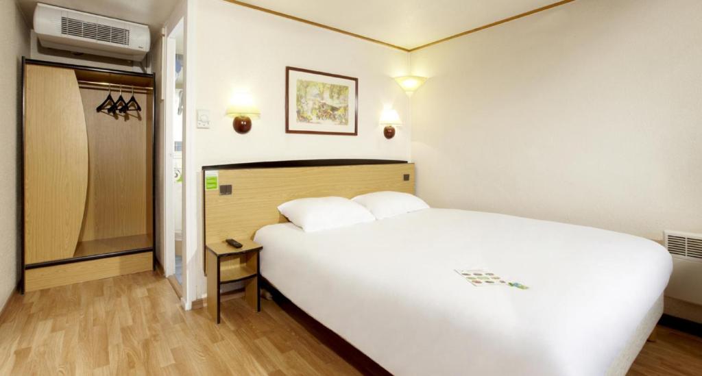 a large white bed in a small room at Campanile Villefranche-Sur-Saône in Villefranche-sur-Saône