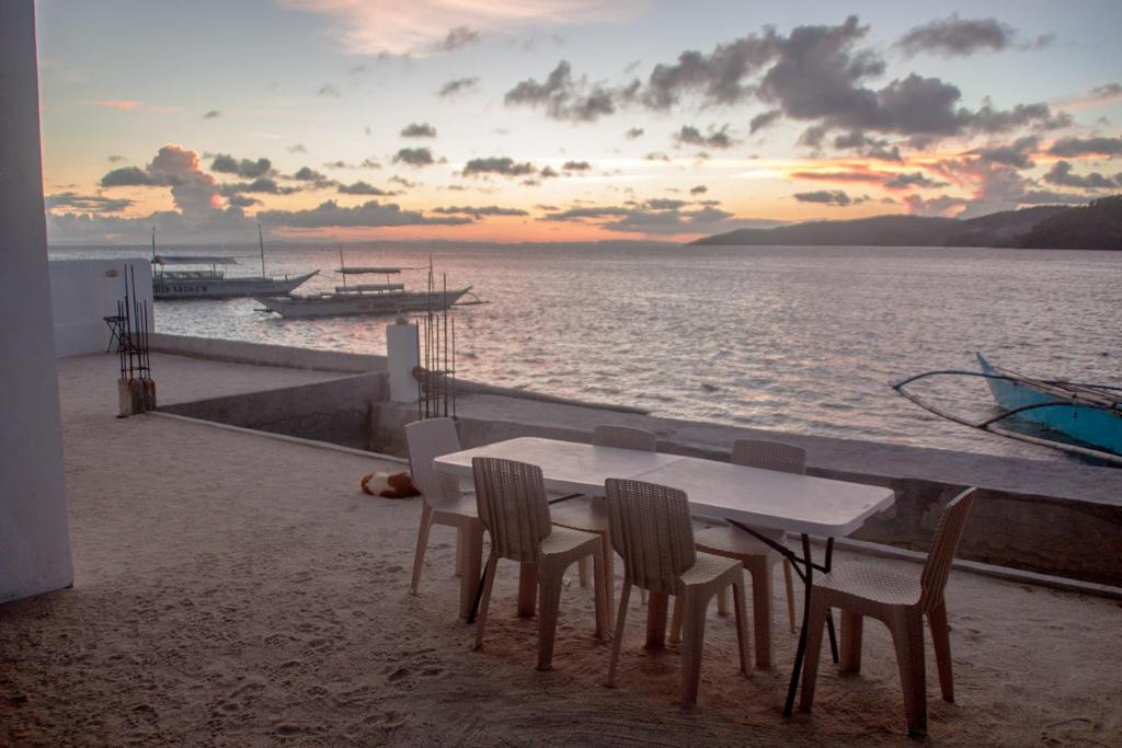 a table and chairs on a balcony with a view of the water at Sunset Beach House in Matnog