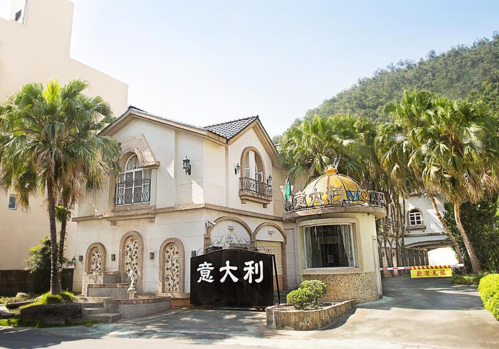 a large house with palm trees in front of it at 意大利商務溫泉汽車旅館 in Jiaoxi