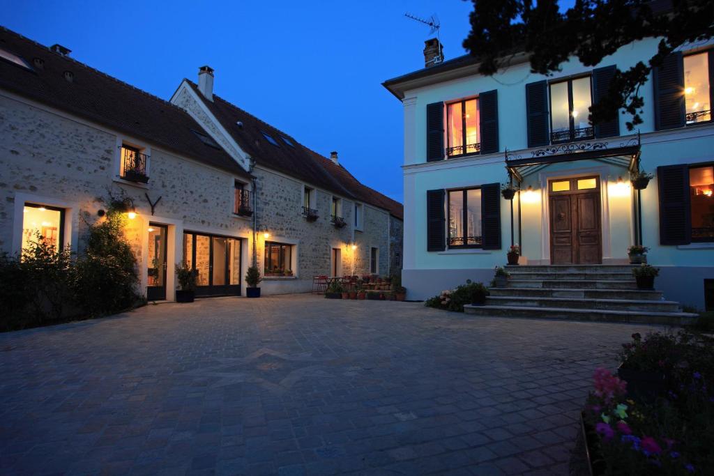 an empty courtyard of a white building at night at Maison d'hôtes LES RAINETTES in Breuillet