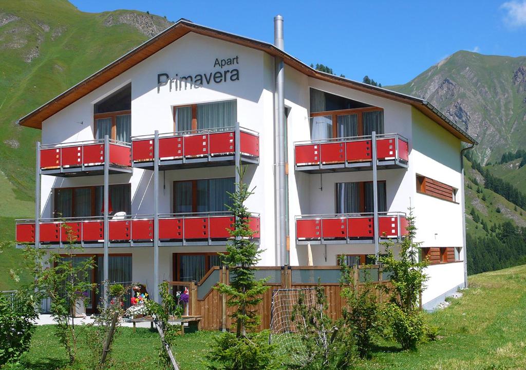 a building with red balconies on a mountain at Apart Primavera in Samnaun