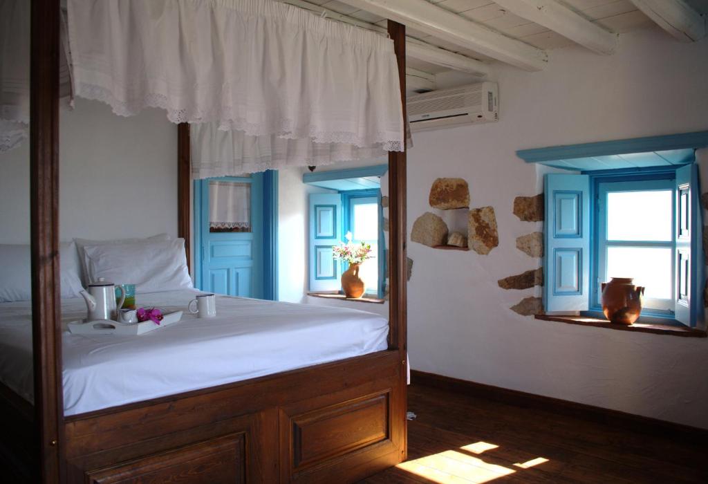 a bedroom with a large bed and two windows at Eirini Luxury Hotel Villas in Grikos