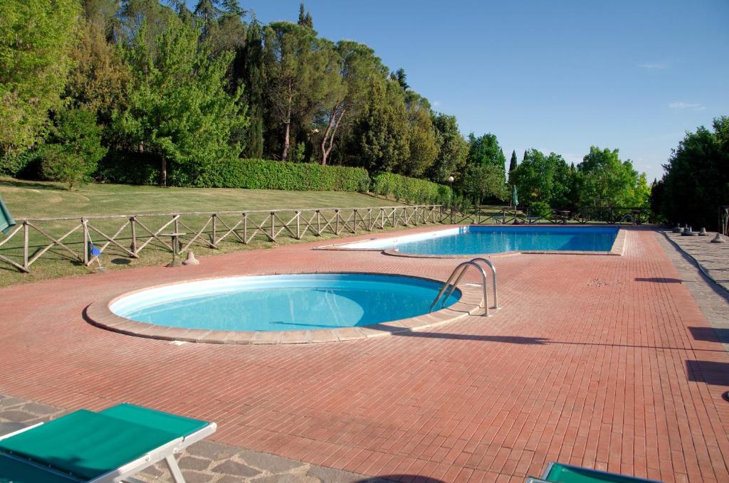 2 piscines sur un patio en briques dans l'établissement Le Gorghe di Valmarino, à Corciano