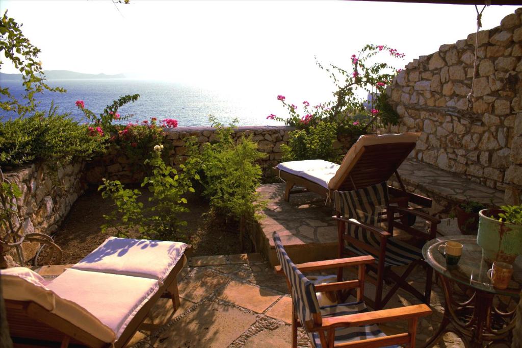 a patio with chairs and a table and the ocean at Eirini Luxury Hotel Villas in Grikos