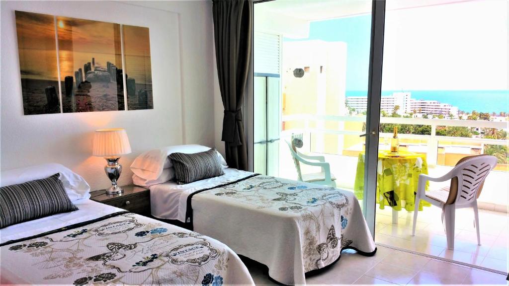 プラヤ・デ・ラス・アメリカスにあるLas Americas Panoramic Sea Viewsのベッド2台とバルコニーが備わるホテルルームです。