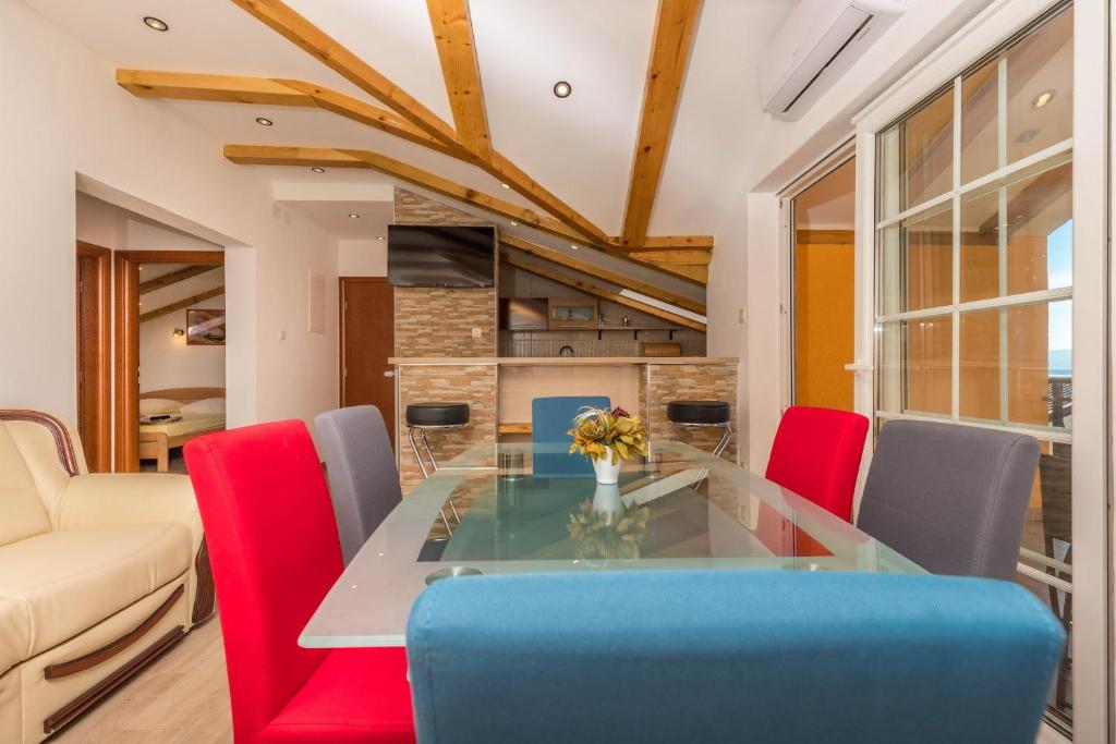 a dining room with a glass table and red chairs at APARTMAN ŠARE in Crikvenica
