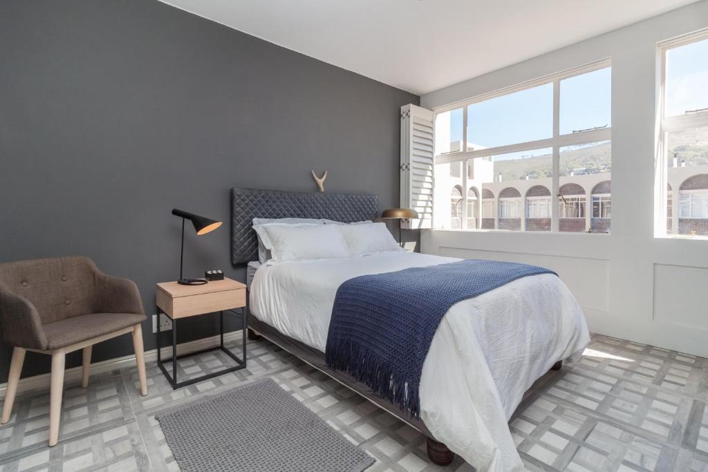ein Schlafzimmer mit einem Bett, einem Stuhl und einem Fenster in der Unterkunft Keerom 66 - Beautiful modern apartment in heart of Cape Town in Kapstadt