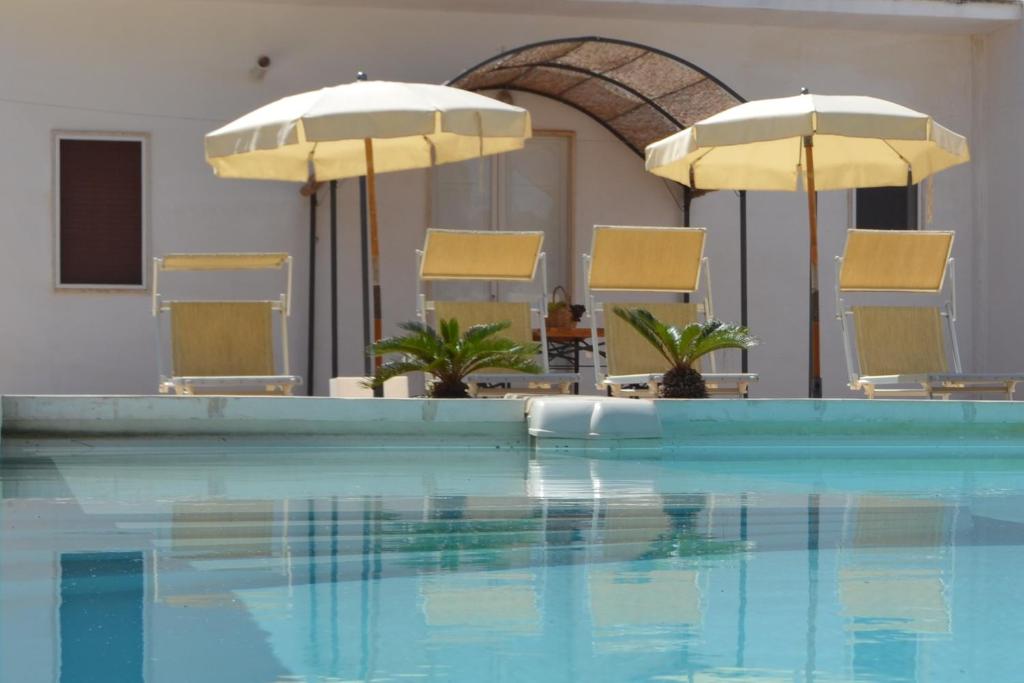 een zwembad met stoelen en parasols in een hotel bij Villa Graziella in Ostuni