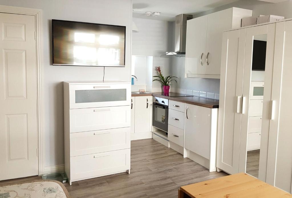 uma cozinha branca com armários brancos e uma mesa em Townhouse in Centre of Cobh em Cobh
