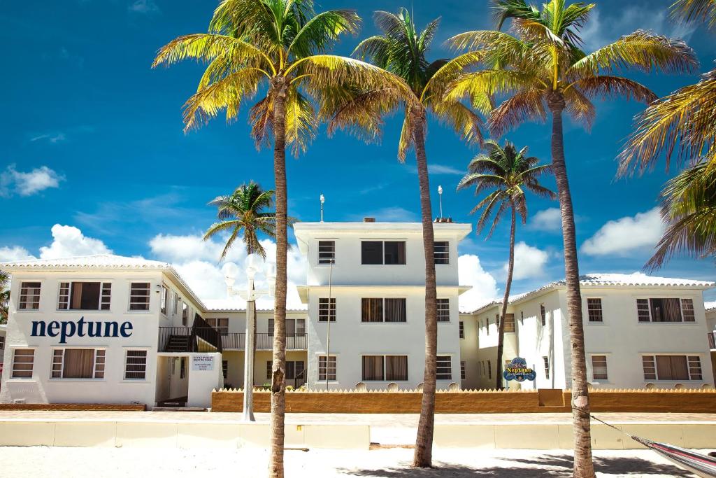 a white building with palm trees in front of it at Neptune Oceanfront Rentals in Hollywood