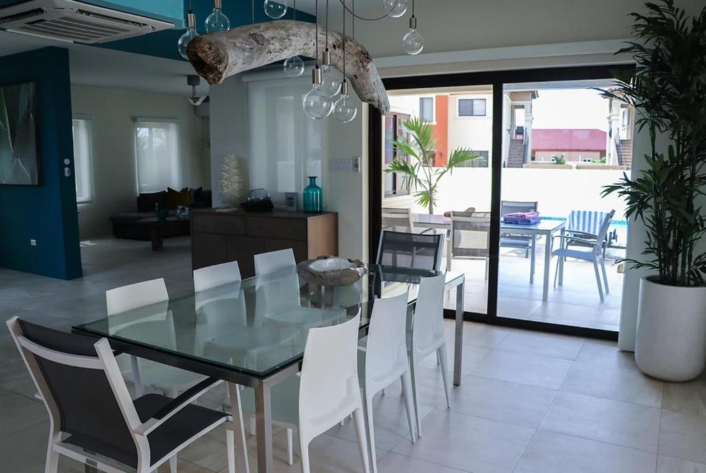 a dining room with a glass table and white chairs at Diamante 181 Luxury home in Gold Coast 4 Bedrooms 3 Bath in Palm-Eagle Beach