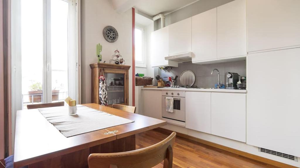 eine Küche mit einem Holztisch und weißen Schränken in der Unterkunft Stunning apt in the design district in Mailand