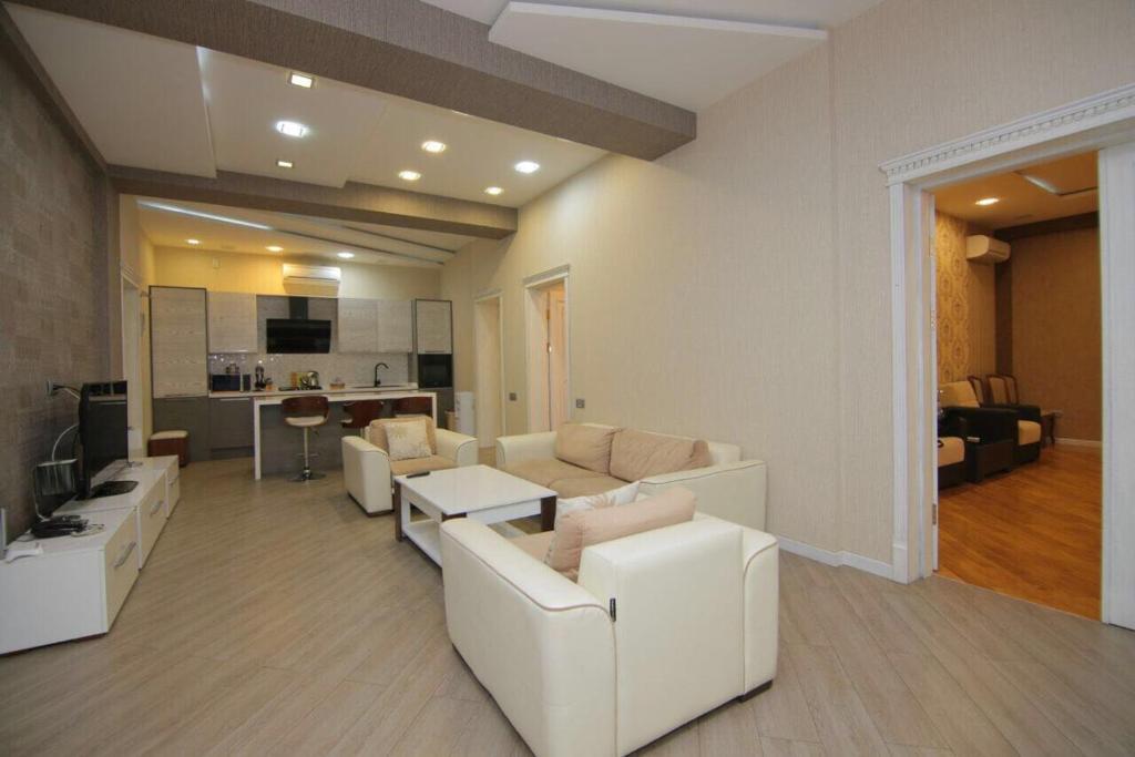 Il comprend un salon avec des canapés blancs et une cuisine. dans l'établissement CENTR BAKU. 4 Bedrooms., à Baku