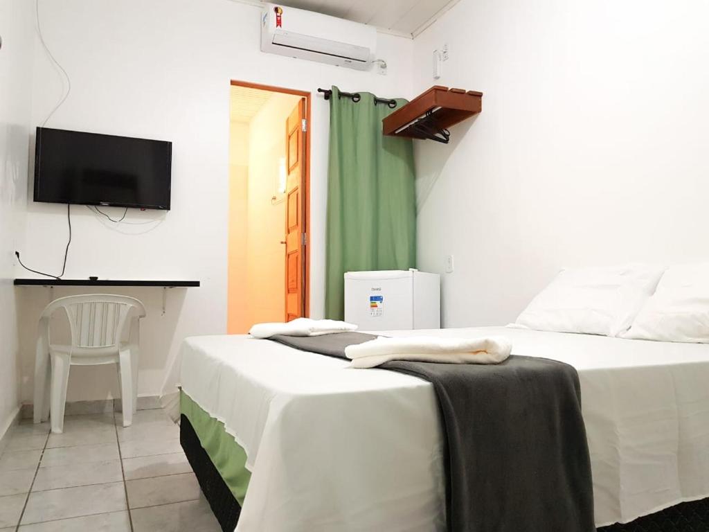 two beds in a room with a tv on the wall at Pousada Amazônia in Rio Branco