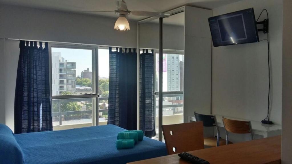 a bedroom with a blue bed and a large window at Uni Medicina in Rosario